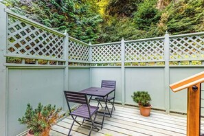 A wooden deck with a lattice fence, a table with chairs, and potted plants.
