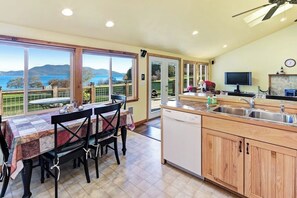 A kitchen with a view of the sea, a dining area with a table and chairs, and a television. - Beachfront Cottage on Buoy Bay with Beach Access and Boat Moor (Eastsound)