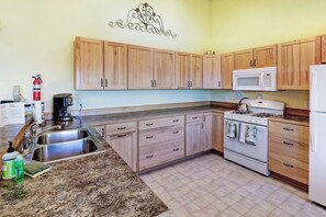 A kitchen with wooden cabinets, a stainless steel sink, a microwave, and a stove.