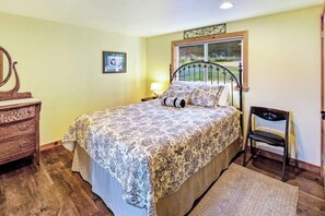A bedroom with a bed, a dresser, a chair, a window with a view, and a wall-mounted artwork.