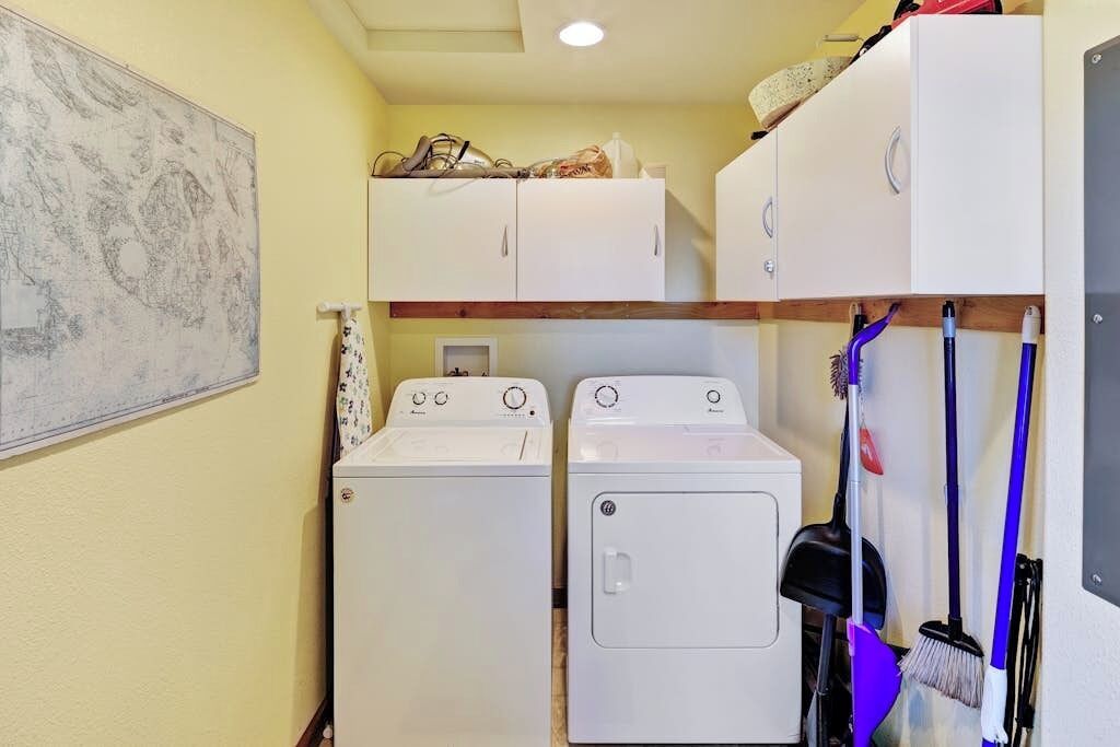 A laundry room with two washing machines, a drying rack, and a broom.