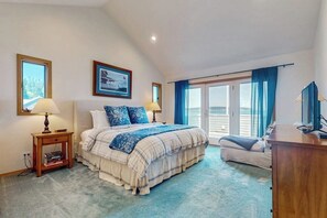 A bedroom with a bed, a nightstand, a dresser, and a large window with curtains. - Charming Waterfront Home in Greenbank with Direct Beach Access and Stunning Ocean Views (Greenbank)