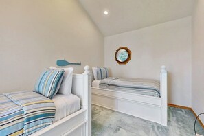 Ein Schlafzimmer mit zwei Betten, eines mit gestreifter Bettwäsche und das andere mit schlichter Bettwäsche.