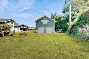 A residential property with a well-maintained lawn, a detached garage, and a house with a gabled roof. - Charming Waterfront Home in Greenbank with Direct Beach Access and Stunning Ocean Views (Greenbank)