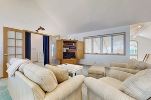 A living room with a sofa set, a television, and a wooden cabinet. - Charming Waterfront Home in Greenbank with Direct Beach Access and Stunning Ocean Views (Greenbank)