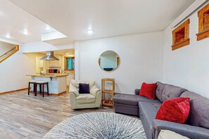 A modern living room with a grey sofa, a round rug, and a small round mirror on the wall. - Peaceful 1BR Pet Friendly House Near Langley (Langley)
