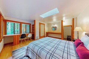Ein Schlafzimmer mit einem großen Bett, einem Schreibtisch und einem Dachfenster.