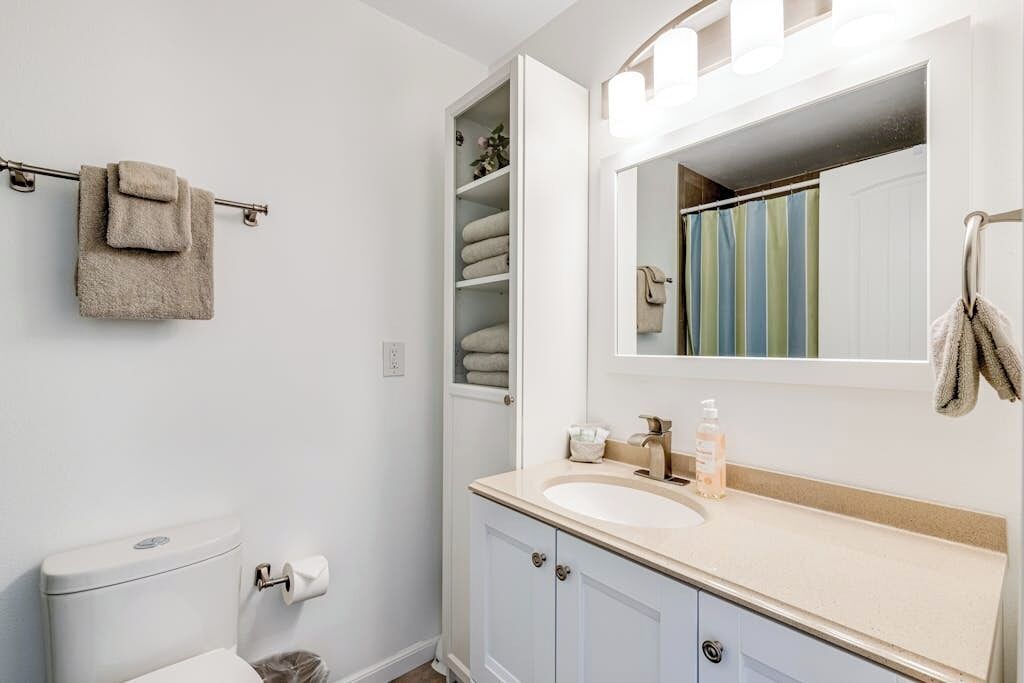 A bathroom with a toilet, a sink with a mirror, and a towel rack.