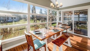 Un comedor con mesa de madera dispuesta para cuatro personas, ventanas amplias y vistas al exterior.