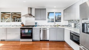 Una cocina moderna con electrodomésticos de acero inoxidable, armarios grises y piso de madera.