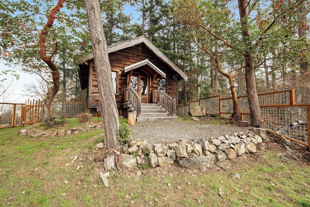 A rustic cabin with a wooden exterior, a porch, and a stone foundation.