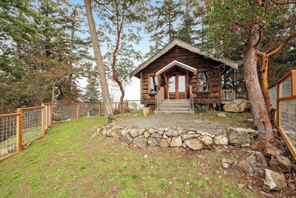 Un chalet rustique avec des fondations en pierre, une terrasse en bois et un espace clôturé.