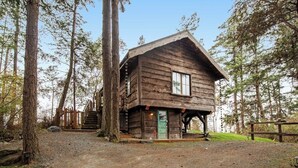 Eine rustikale Holzhütte mit einer Veranda und einer Treppe zu einer Terrasse.