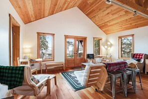 Una habitación acogedora con techo inclinado, piso de madera, cama, escritorio y televisor.