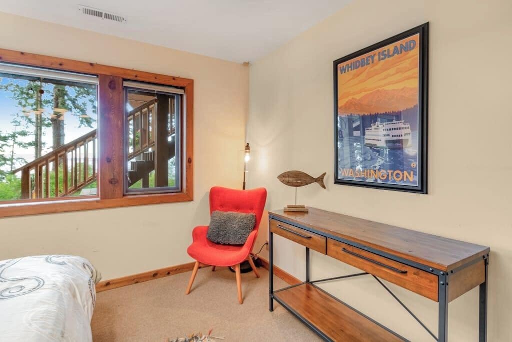 Une pièce comprenant un lit, un bureau, une chaise, une fenêtre donnant sur des arbres et une affiche accrochée au mur.