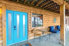 Une cabane en bois avec une porte bleue, une table ronde entourée de chaises et une grande fenêtre.