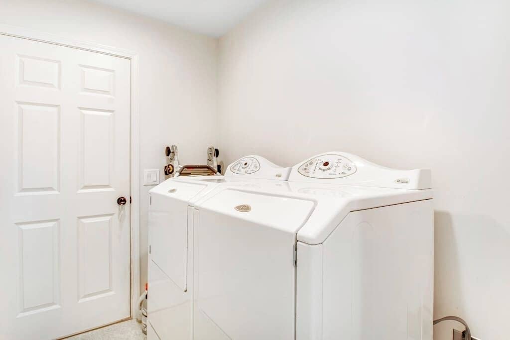 A laundry room with a white door, a washing machine, and a dryer.