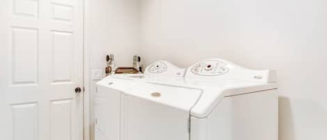 A laundry room with a white door, a washing machine, and a dryer.