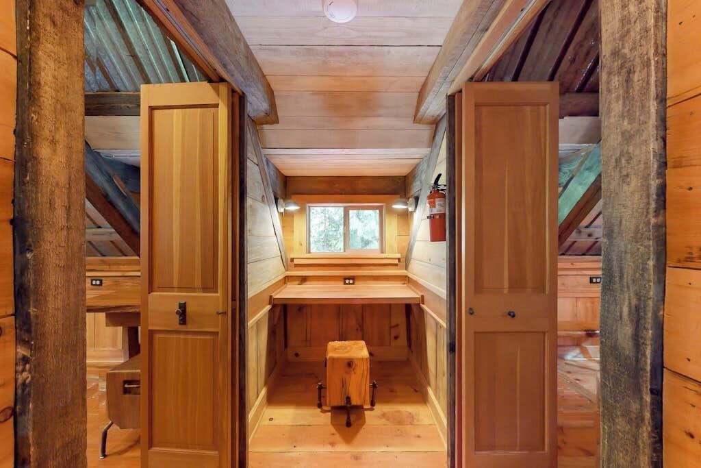 A wooden interior with a bench, a window, and a fire extinguisher.