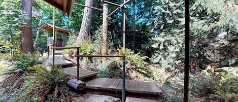 A wooden structure with a metal framework, surrounded by dense forest.