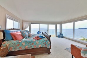 Una camera da letto con un letto grande, vista sul mare e un balcone con ringhiera.