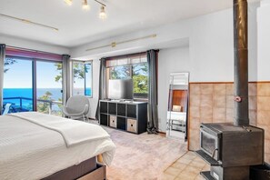 Habitación de hotel con cama, escritorio, televisión, chimenea y vista al océano.