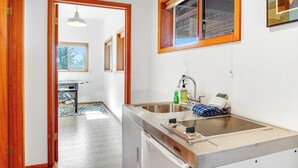 A compact kitchen with a built-in stove, a sink, and a window above it. - Stunning Mountaintop Retreat with Private Sauna and Water Views (Eastsound)