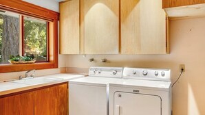 A kitchen with wooden cabinets, a built-in sink, and a white stove. - Stunning Mountaintop Retreat with Private Sauna and Water Views (Eastsound)
