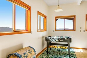 Habitación con mesa de fútbol de mesa con el rótulo 'STAR WARS', ventanas amplias y una lámpara de techo.