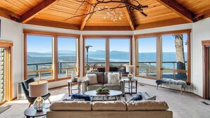 A spacious room with a high ceiling, large windows, and a view of the outdoors. - Stunning Mountaintop Retreat with Private Sauna and Water Views (Eastsound)