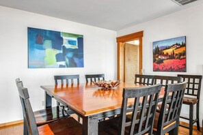 Zona pranzo con tavolo e sedie in legno, un centrotavola in una ciotola e due quadri alle pareti.