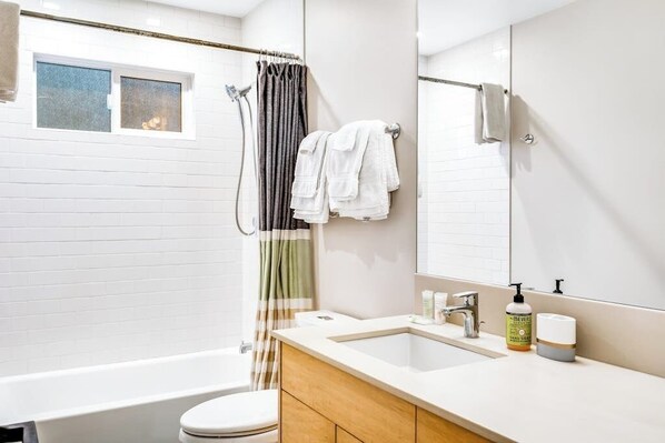 A modern bathroom with a bathtub, toilet, and a vanity with a mirror. - Accessible Waterfront Holiday Home with Bay Views and Family Friendly Features (Lopez Island)