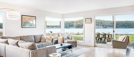 A spacious living room with a large sofa, a coffee table, and a view of a lake.