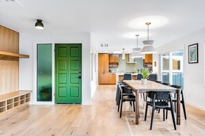 Una cocina moderna con armarios de madera, una mesa de comedor con sillas e iluminación colgante.