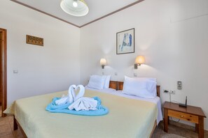 Ein Hotelzimmer mit einem Bett, zwei Nachttischlampen, einem Bild an der Wand und einem Holznachttisch mit einem Telefon.
