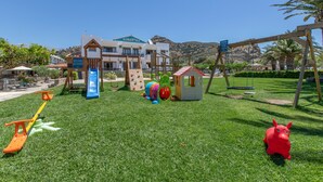 A playground with a slide, swings, and climbing structures. - Family Beachfront Apartment with Sea View in Agia Galini, Crete (Agia Galini)