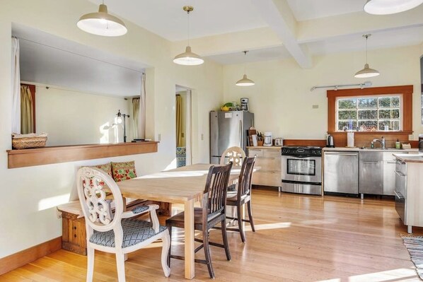 Una cocina con una mesa de comedor, sillas, un refrigerador, un horno y una ventana.