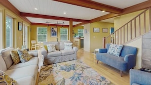 A spacious living area with a high ceiling, wooden beams, and a staircase leading to an upper level. - Renovated 3 Bedroom Eastsound Home with Hot Tub Fire Pit and Stunning Sound Views (Eastsound)