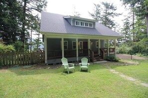 Een huis met een veranda, twee stoelen en een gazon.