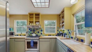 A kitchen with a stove, oven, microwave, and a window above the sink. - Renovated 3 Bedroom Eastsound Home with Hot Tub Fire Pit and Stunning Sound Views (Eastsound)