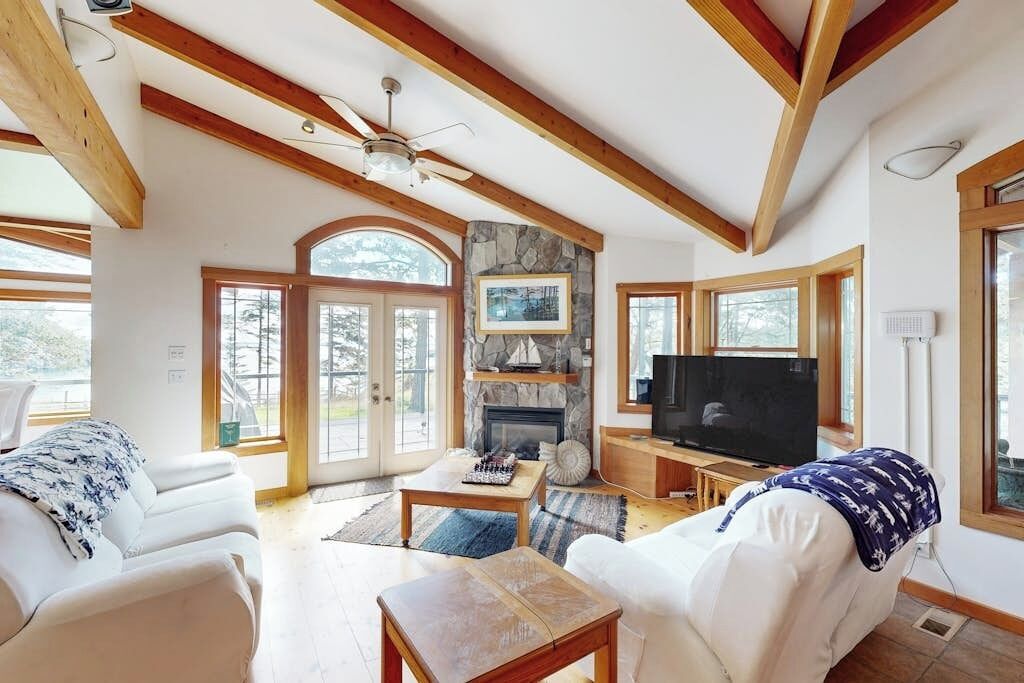 A spacious living room with a fireplace, a television, and a ceiling fan.