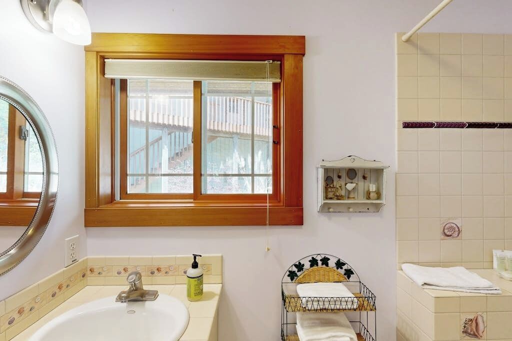 Ein Badezimmer mit Fenster, Waschbecken, Spiegel und Handtuchhalter.