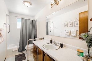 A bathroom with a shower, toilet, sink, and a large mirror. - Relaxing Coastal Retreat with Garden and Water Views in Freeland (Freeland)