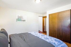A bedroom with a bed, a wardrobe, and a door leading to another room.