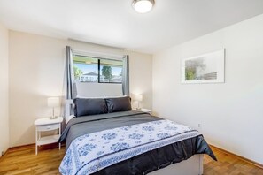 A bedroom with a bed, two bedside tables, a window with curtains, and a framed picture on the wall. - Relaxing Coastal Retreat with Garden and Water Views in Freeland (Freeland)