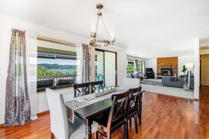 A dining area with a table and chairs, a chandelier, and a view of the outdoors. - Relaxing Coastal Retreat with Garden and Water Views in Freeland (Freeland)