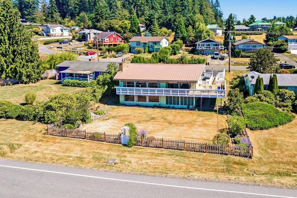 A residential area with houses, a fenced yard, and a road.