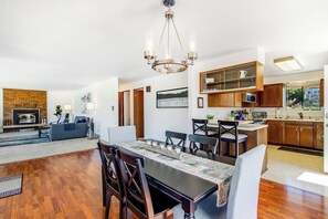 A spacious living area with a dining table, kitchen, and a fireplace.