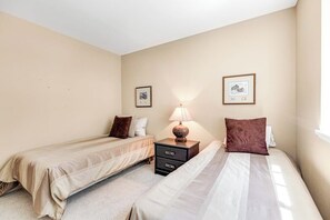 A hotel room with two single beds, a nightstand with a lamp, and two framed pictures on the wall. - 3 BR Waterfront Retreat with Private Beach Access and Stunning Ocean Views (Freeland)