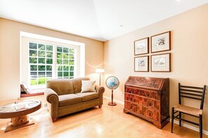 A cozy living room with a sofa, a wooden chest of drawers, a globe, and framed pictures on the wall.